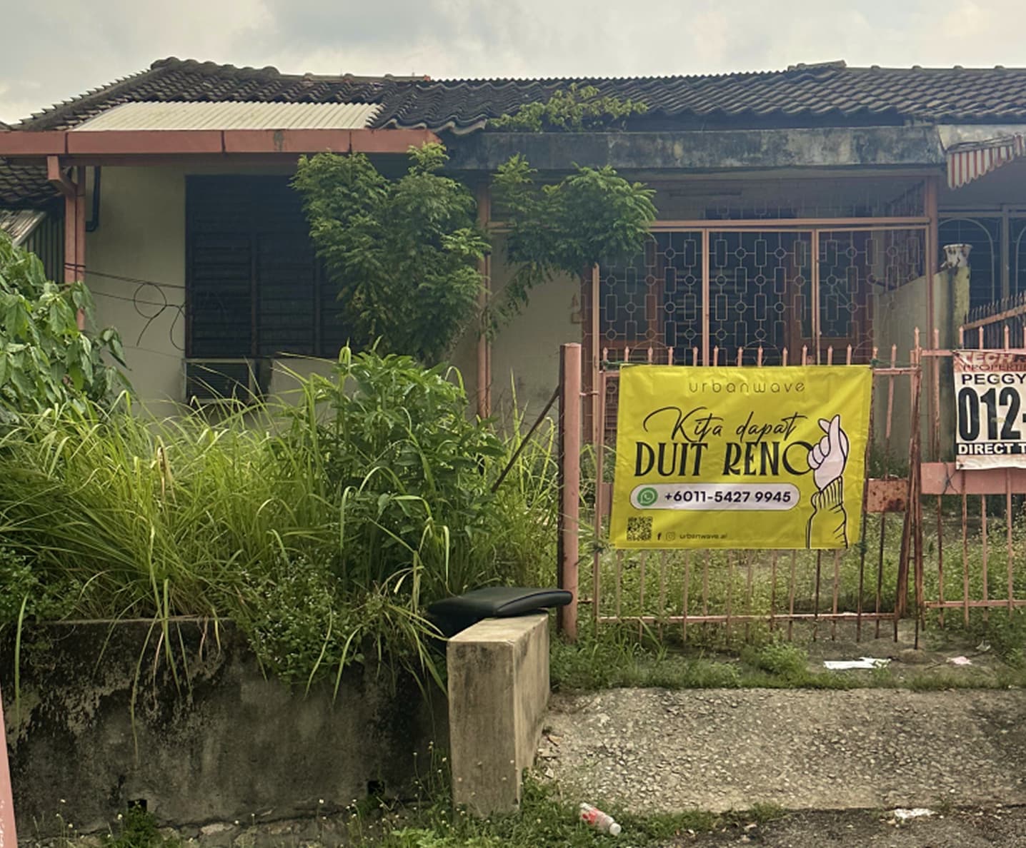 Image of an old Malaysian house with lalang growing everywhere, zinc roof patched and rusty. For sale signs hang on the front